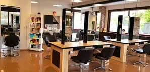 Le salon pédagogique de l'école et CFA Espace Bel Air. Il y a des fauteuils de coupe et des bacs à shampoing. Les couleurs sont noires et marron.